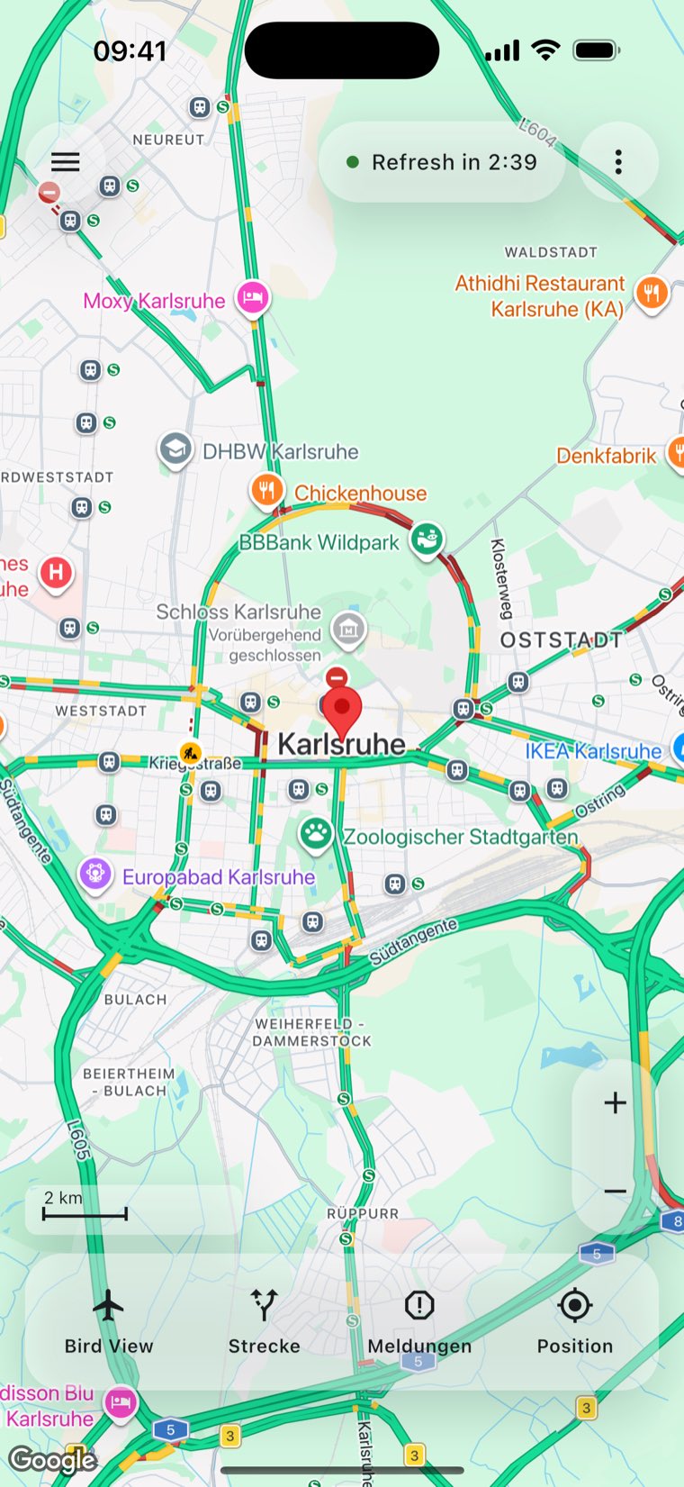 Die Hauptkarte von ACom über Karlsruhe. Die Verkehrslage färbt die Straßen, oben läuft ein Countdown bis zur nächsten Aktualisierung, unten stehen die vier Knöpfe Bird View, Strecke, Meldungen und Position.